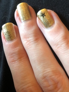 Photo of fingernails painted gold with black stars